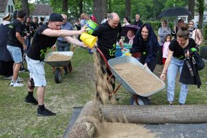 Bischof Dr. Franz Jung hilft beim Befüllen des neuen Sandkastens in der Gemeinschaftsunterkunft Corlette Circle in Kitzingen.