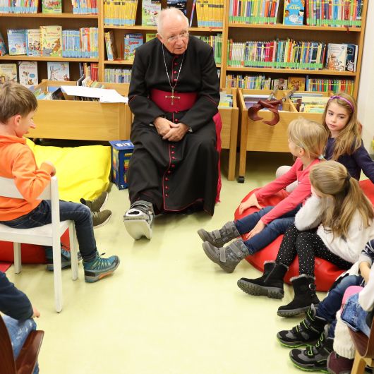 Weihbischof Ulrich Boom erklärte den Kindern auf Nachfrage, warum er am rechten Fuß eine Schiene tragen muss. 