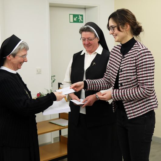 Schwester Tamara Lutz (Mitte), Archivarin der Erlöserschwestern, und Projektleiterin Dr. Lina Hörl (rechts) überreichen ein Findbuch samt CD an Generaloberin Schwester Monika Edinger.