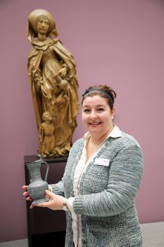 Museumspädagogin Dr. Yvonne Lemke mit einem Krug aus dem Museumsdepot, ähnlich dem, den die Figur der heiligen Elisabeth im Hintergrund in der Hand hält. Sie hofft, dass es die Erinnerungen der Teilnehmer weckt, wenn sie manche Stücke auch anfassen können.