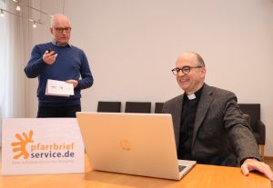 Pastoralreferent Johannes Simon (links), Leiter von pfarrbriefservice.de, erläutert im Würzburger Bischofshaus Bischof Dr. Franz Jung die wichtigsten optischen Veränderungen des Internetportals, das in diesen Tagen seinen 18. Geburtstag feiert. 