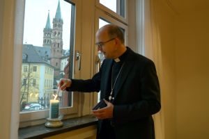 Bischof Dr. Franz Jung entzündet in einem Fenster des Bischofshauses eine Kerze zum Gedenken an die Verstorbenen und deren Angehörige in der Coronakrise.