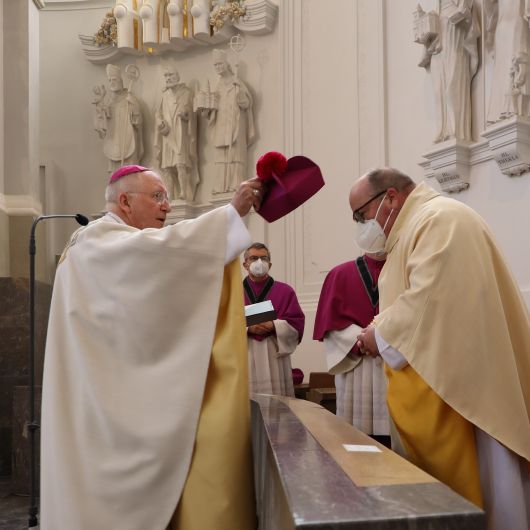 Dompropst Weihbischof Ulrich Boom (links) führte Domkapitular Stefan Gessner an seinen Platz im Chorgestühl des Kiliansdoms und setzte ihm das Birett auf. 