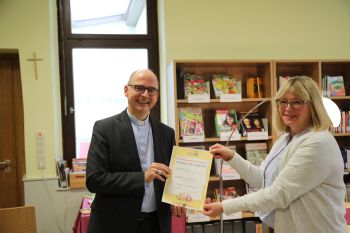 Karin Gerhard,  Leiterin der Katholischen Öffentlichen Bücherei Retzstadt, überreicht dem Bischof eine Urkunde als "Vorleser".