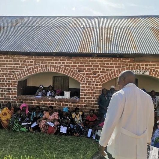 Dr. Daniel Kirumbi stellt den Patientinnen und Patienten in Nangombo das Angebot der Mobilen Klinik vor.