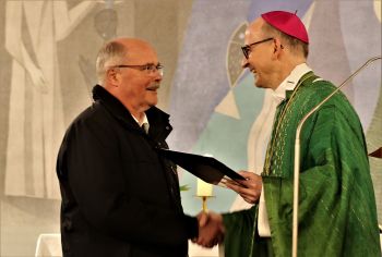 Bischof Dr. Franz Jung (rechts) überreicht Pfarrer i. R. Alfred Kraus die päpstliche Ernennungsurkunde zum Monsignore.
