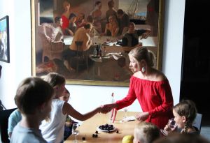 Veranstaltung "Nachts im Museum" im Museum am Dom:  Museumsführerin Sandra Miara-Hegent (im roten Kleid) begrüßt die Kinder. Sie verkörpert eine Figur aus dem Gemälde "Die Würfel" von Paulis Postažs.