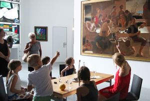 Veranstaltung "Nachts im Museum" im Museum am Dom:  Museumsführerin Sandra Miara-Hegent (im roten Kleid) lässt sich von den Kindern erklären, was im Bild "Die Würfel" von Paulis Postažs alles zu sehen ist.